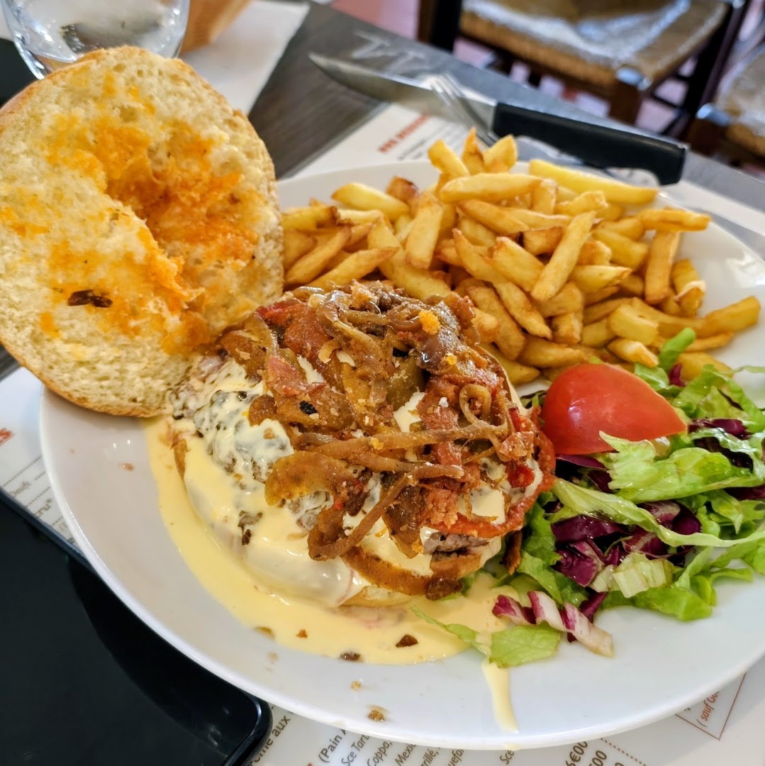 Un burger avec oignons, frites et salade