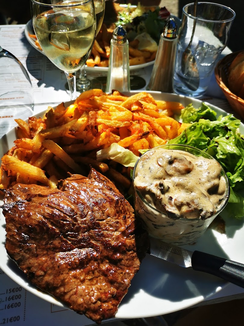 Une viande grillée avec frites, salade et sauce aux champignons